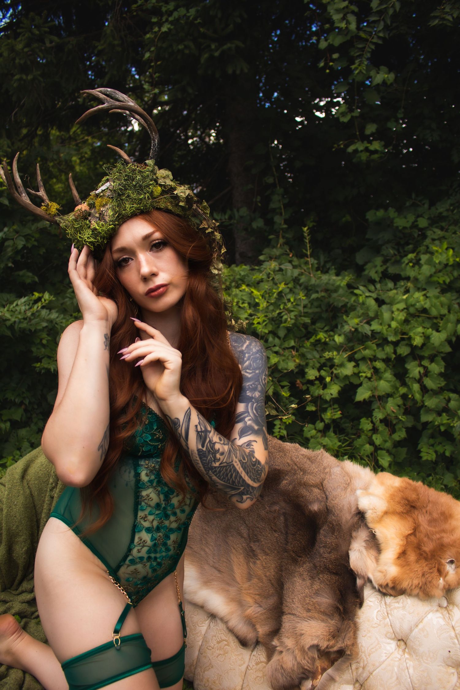 Person in green lingerie poses with floral crown and tattoos alongside golden retriever.