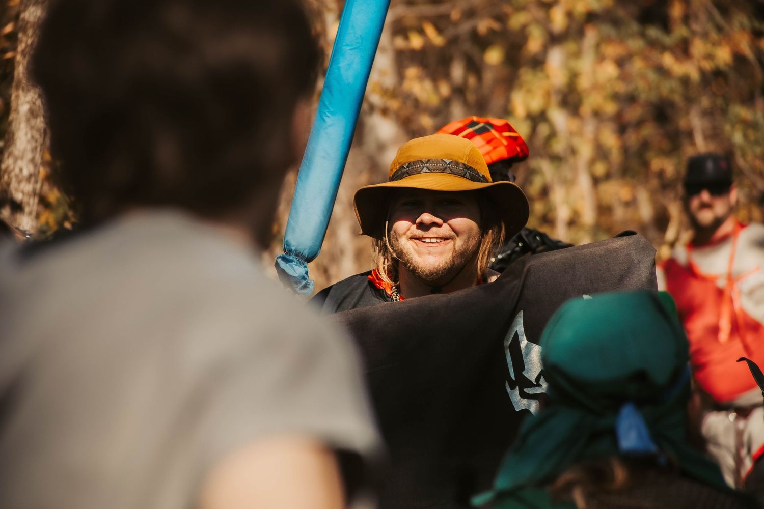 Person wearing a hat smiles during an outdoor activity on a sunny autumn day.