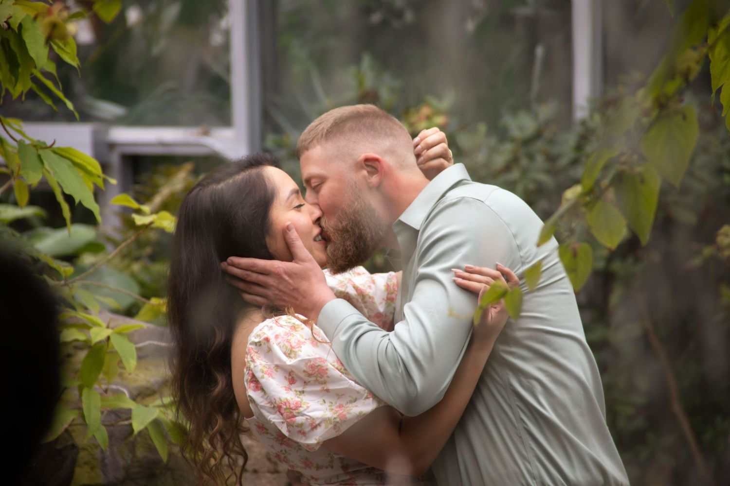 A romantic series of candid moments between a couple embracing in front of foliage during an intimate celebration.