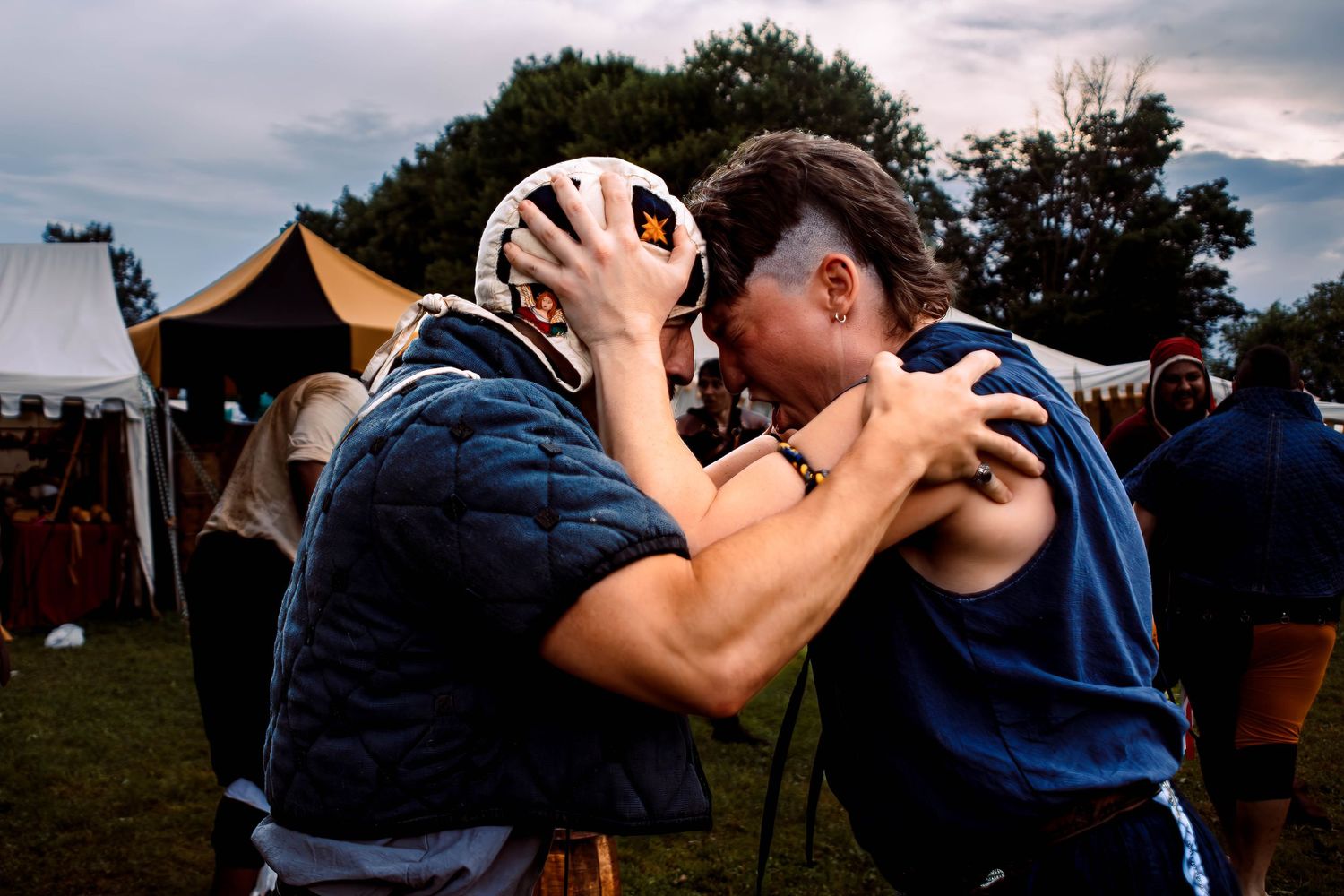 A sequence of people drinking from a shared beverage container at an outdoor festival or gathering.