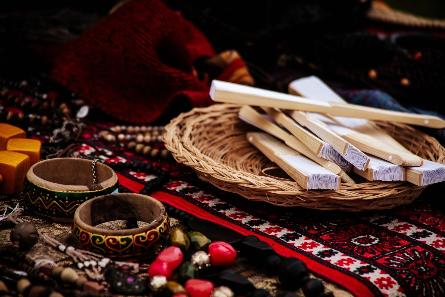 Traditional Native American artifacts including beaded moccasins, leather goods, and woven textiles displayed on red fabric.