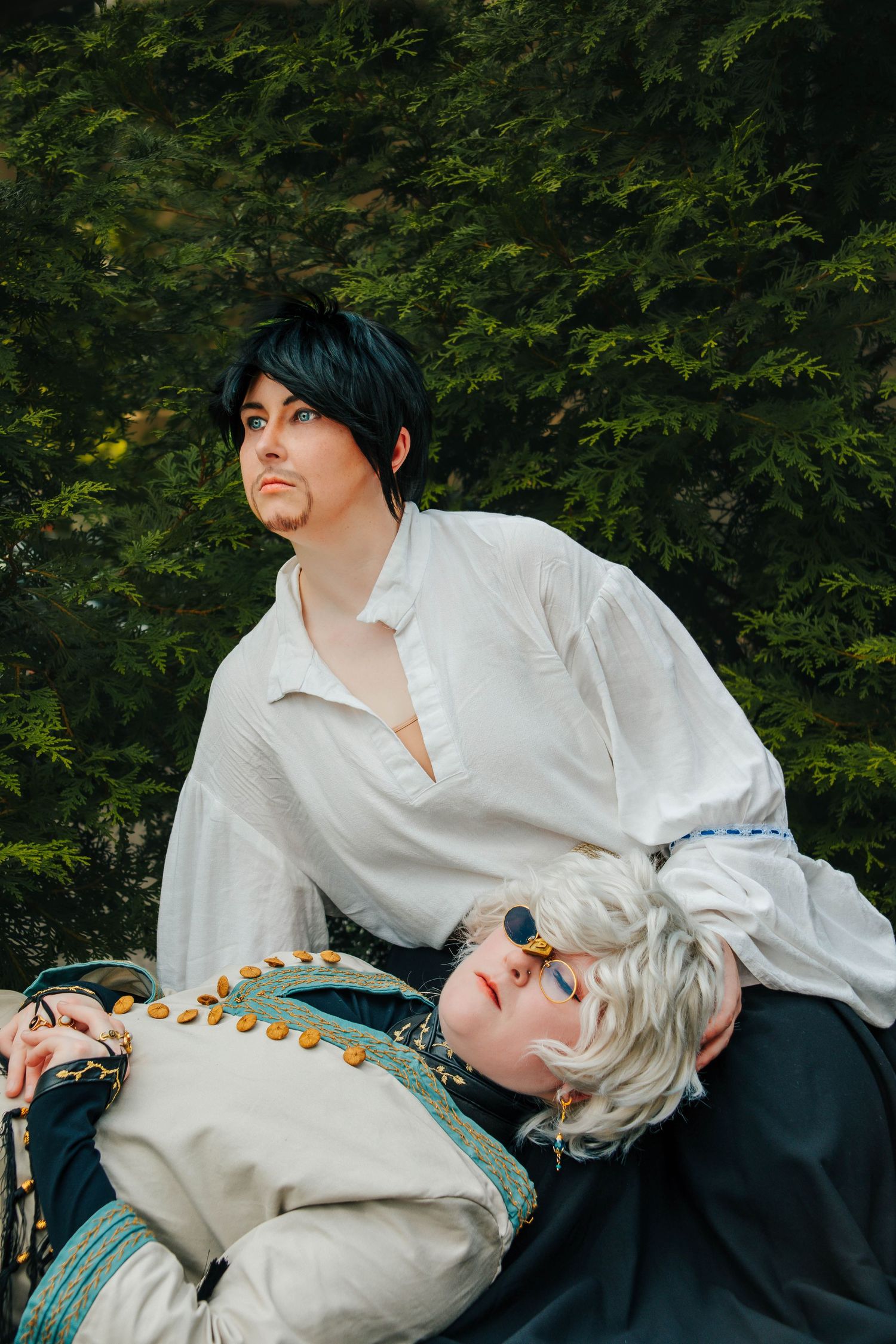 A dramatic scene depicting a romantic couple in period costumes against a green foliage background.