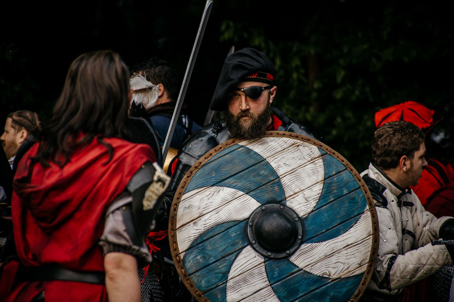Medieval reenactors in battle gear with a Viking shield and sword at a historical combat event.