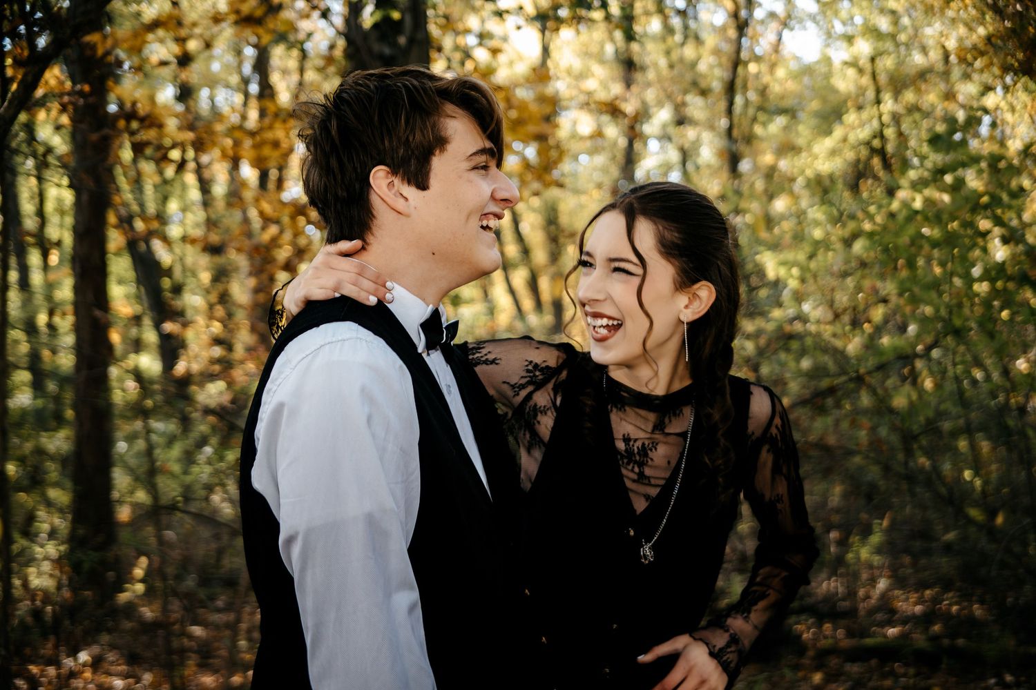 Couple sharing a joyful moment together in a sunlit forest setting.