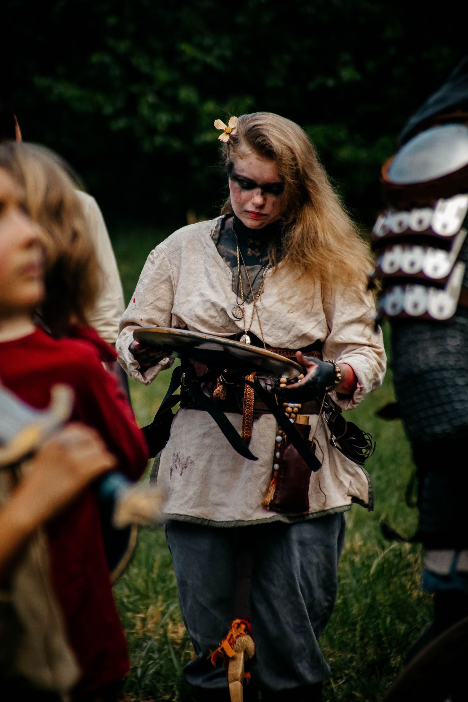 A person in medieval costume holds a crossbow during an outdoor historical reenactment event.