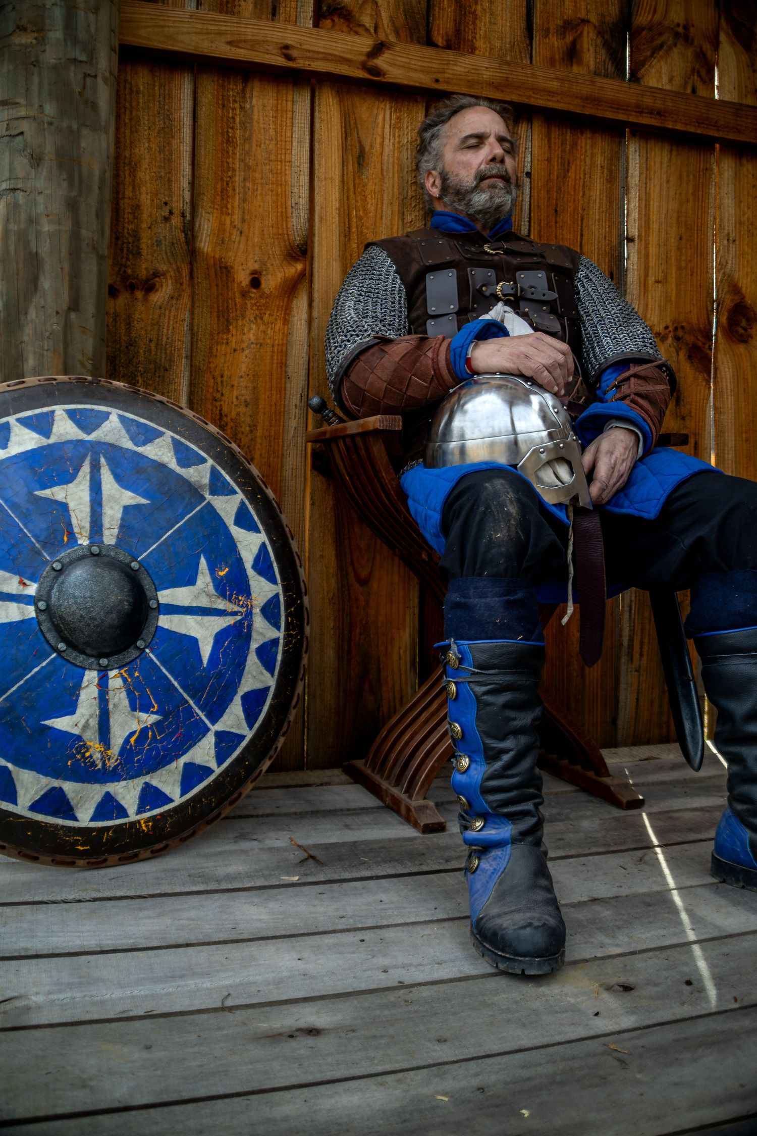 A sequence showing a person in medieval armor sitting against a wooden wall with a shield decorated with blue stars.