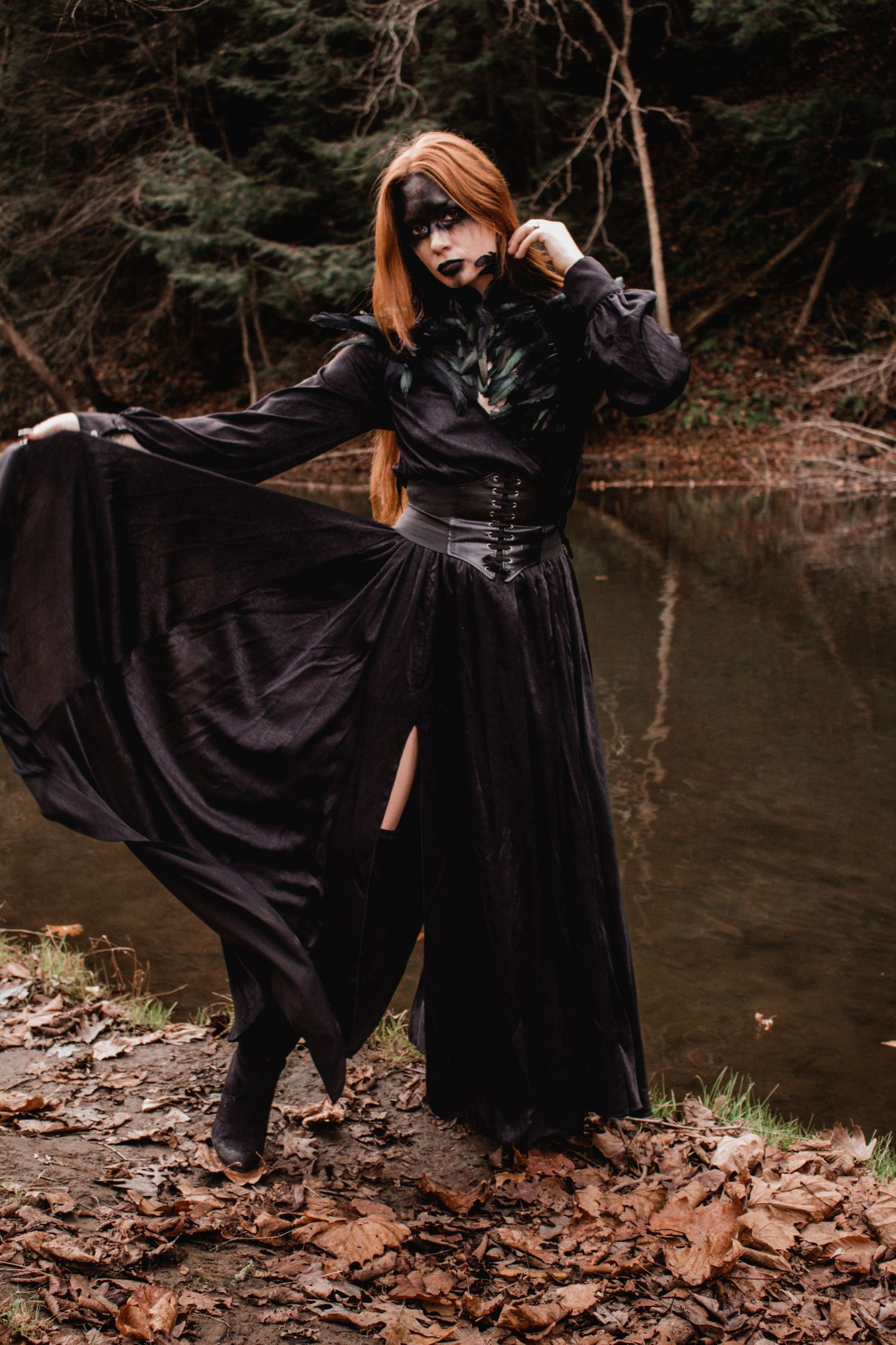 Dramatic flowing black dress captured in motion near a woodland stream.