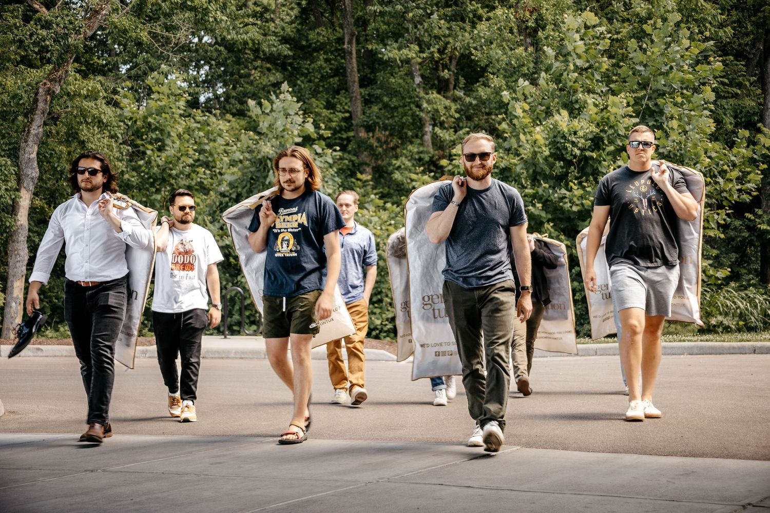A casual group walks together outdoors on a sunny day wearing sunglasses.