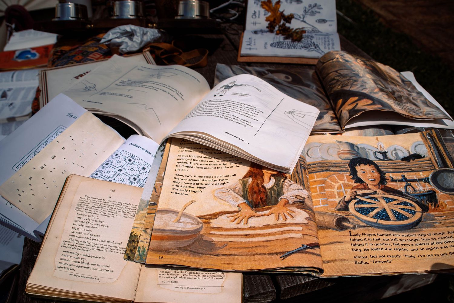 Open books and papers scattered across a wooden desk with handwritten notes and study materials in warm lighting.