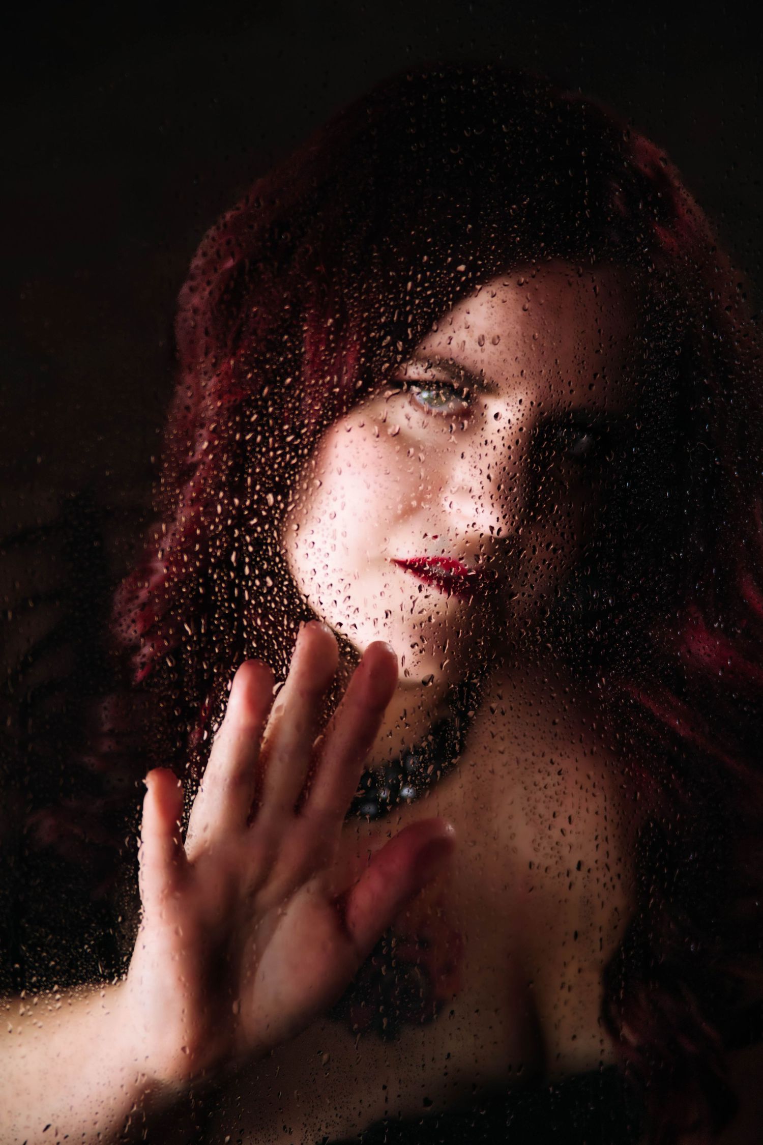 Artistic sequence showing a hand pressing against wet glass with red lighting creating a moody atmospheric effect.