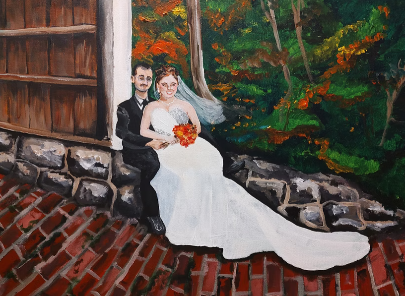 A couple sits together on brick steps against a stone wall with autumn foliage in the background.