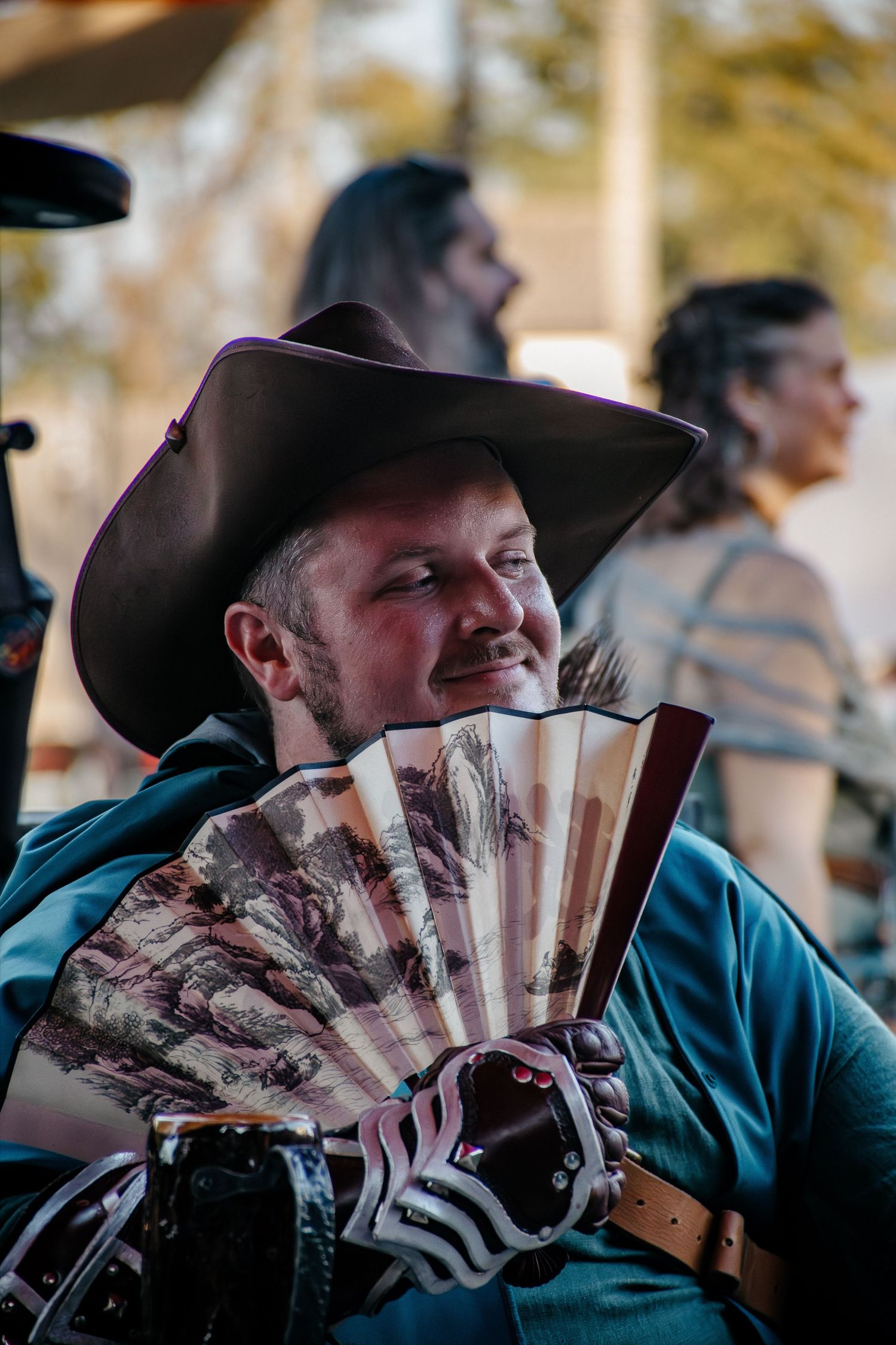 Performer in period costume and cowboy hat plays traditional instruments at historical event.