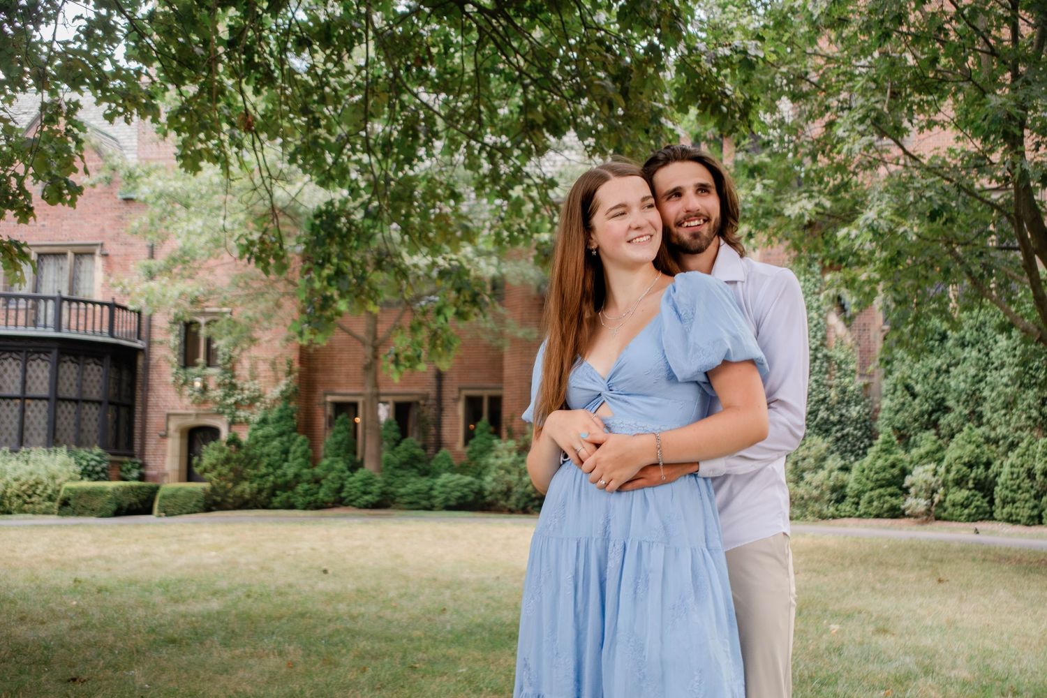 Romantic outdoor portraits in a garden setting with brick buildings in background.