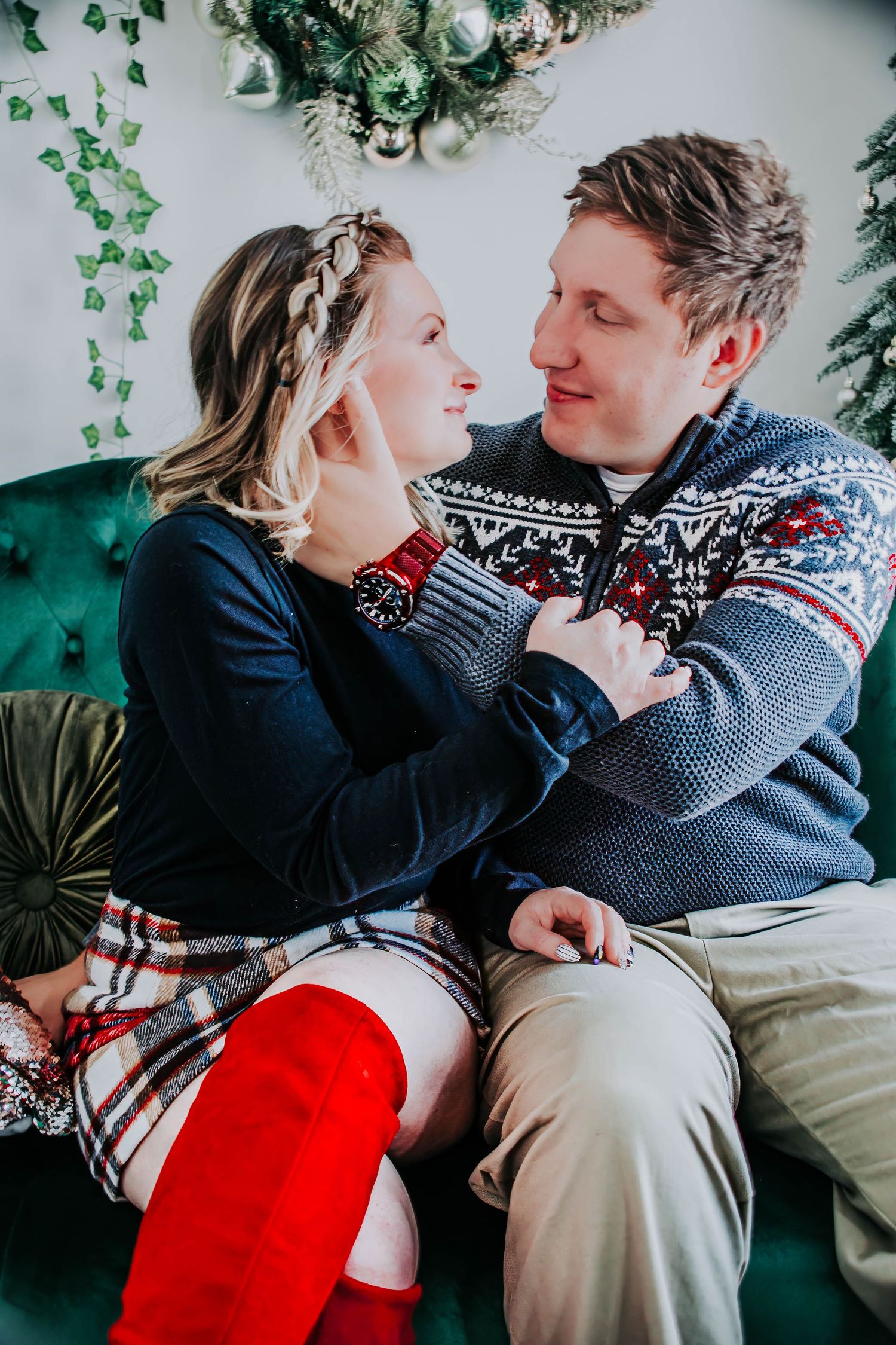 Indoor couple photoshoot with a red skirt and Nordic sweater in a festive holiday setting.