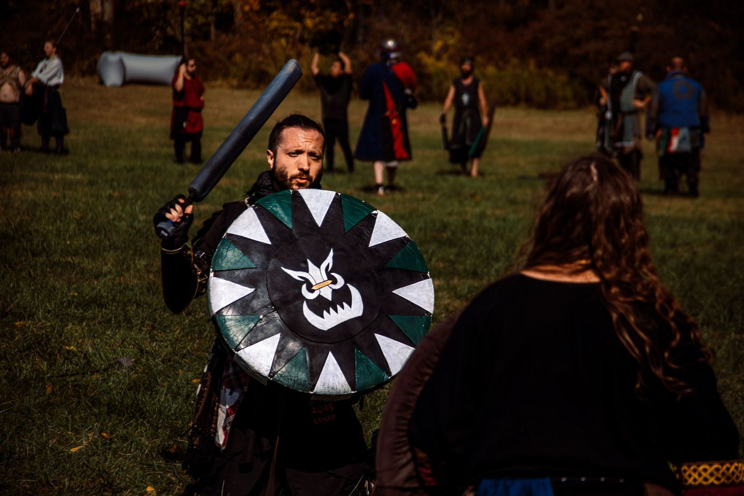 A group of people fly colorful kites in a grassy field on a sunny autumn day.
