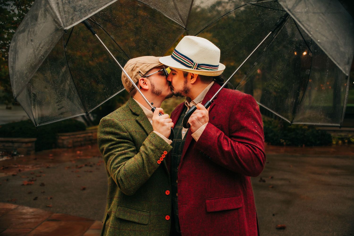 A couple shares an intimate moment under umbrellas in a romantic outdoor setting during rainfall.