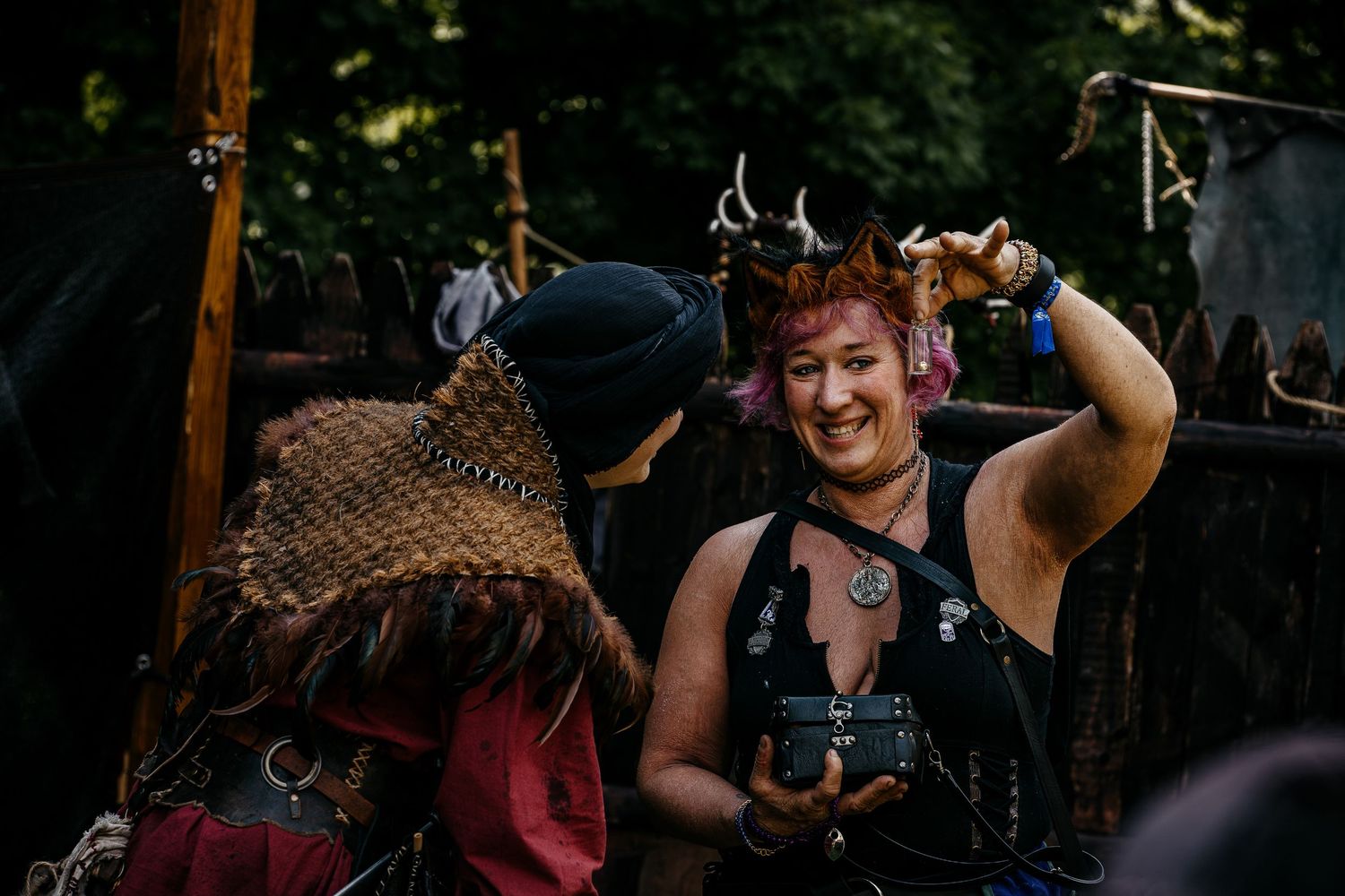 Woman in fantasy costume with deer horns smiles at a Renaissance faire outdoor event.