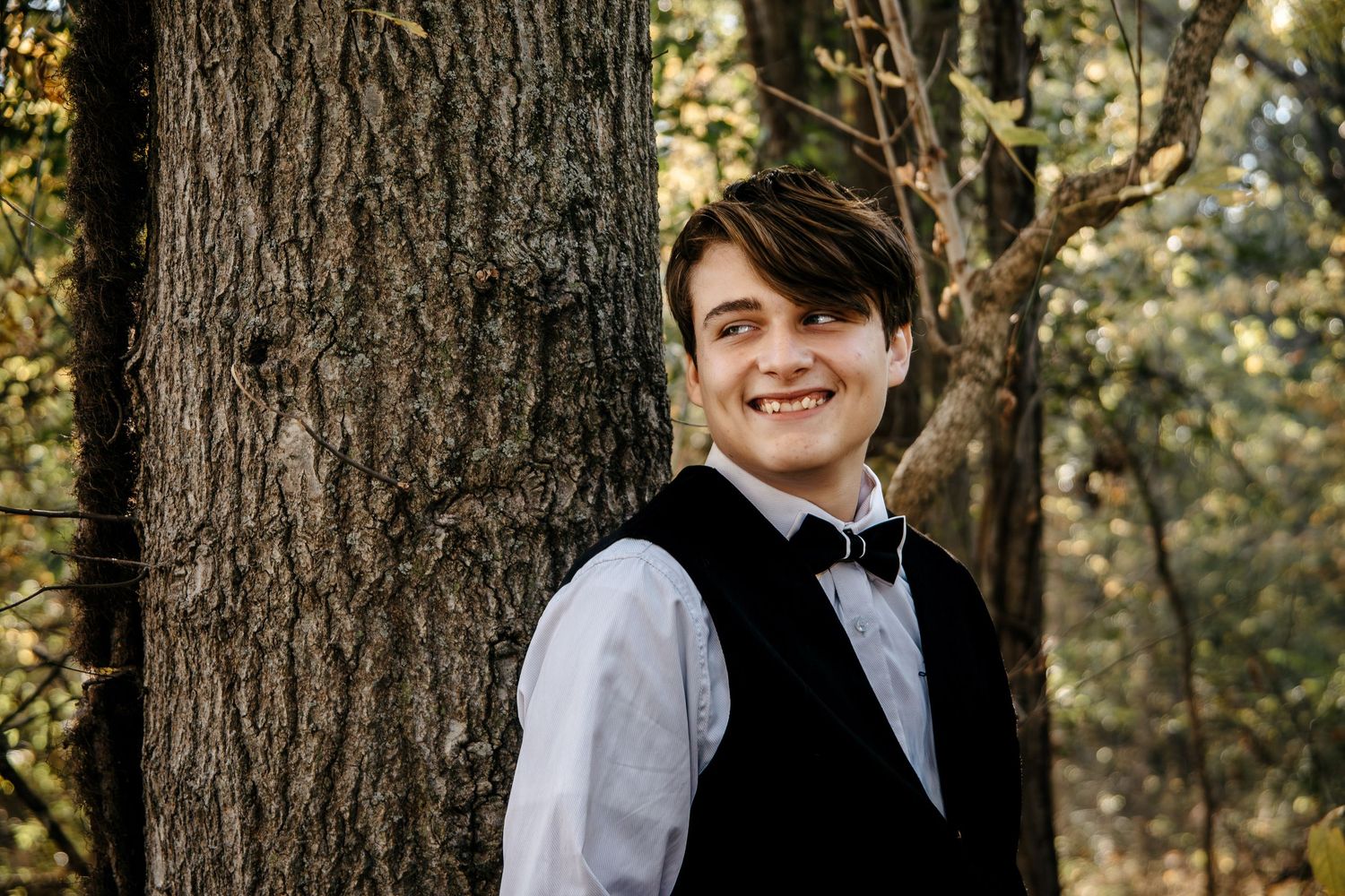 Formal portraits taken against rustic tree trunk backdrop in natural setting.
