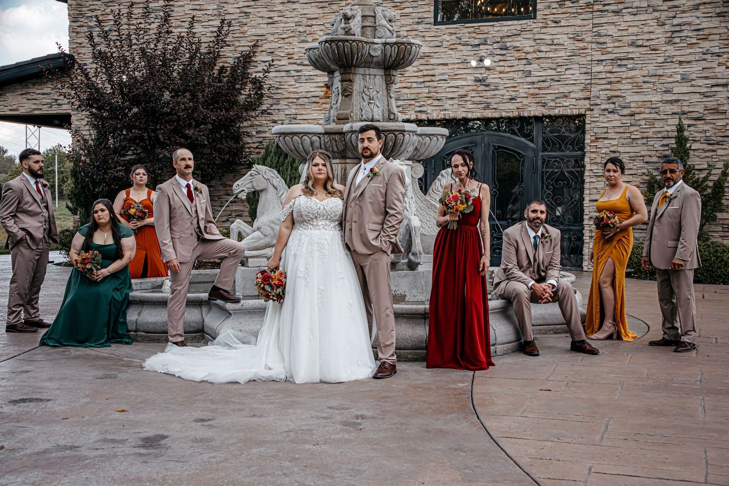 Wedding party and guests gathered outside a stone building during ceremony.