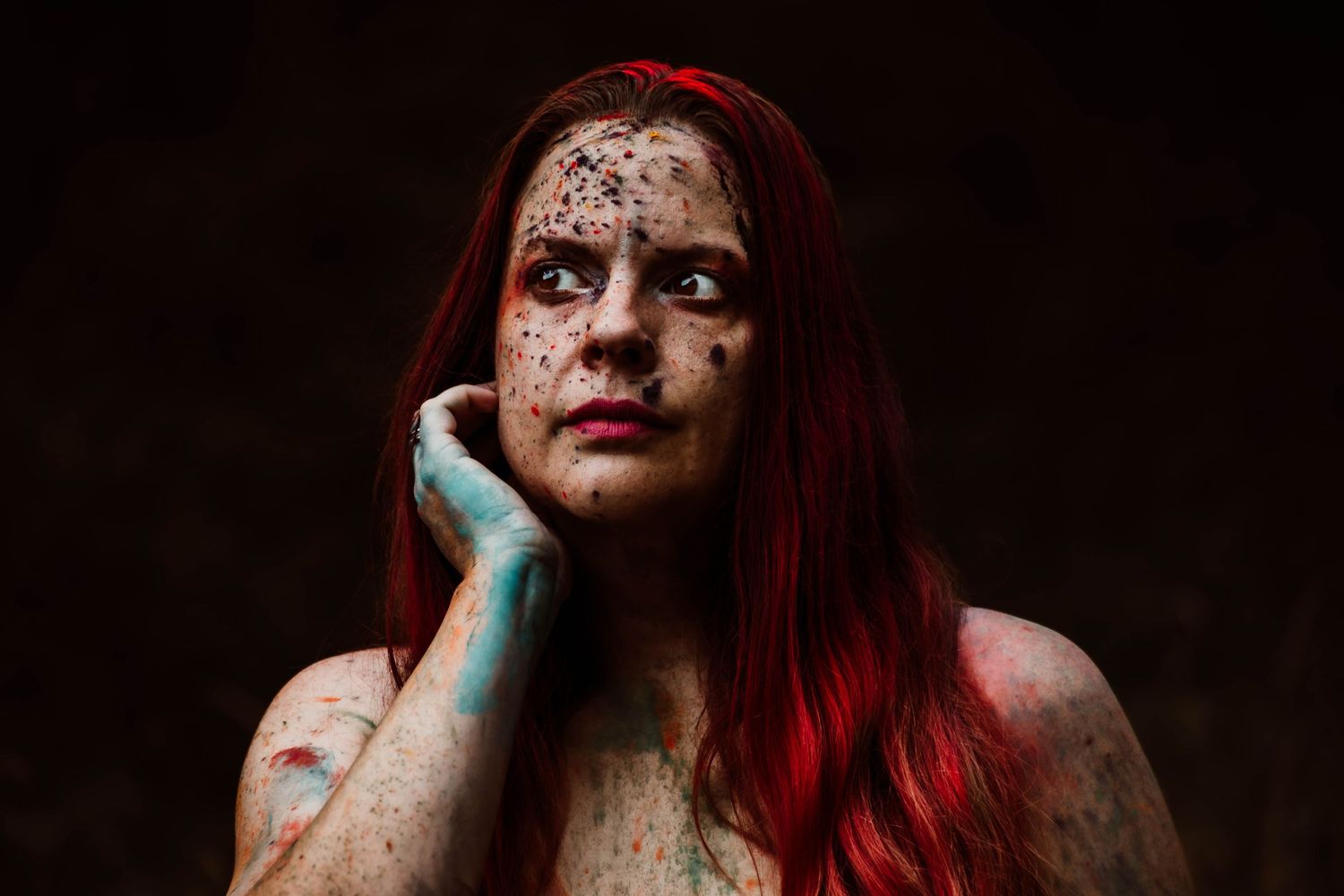 Portrait series showing a person with vibrant red hair in dramatic lighting and dark gothic makeup.