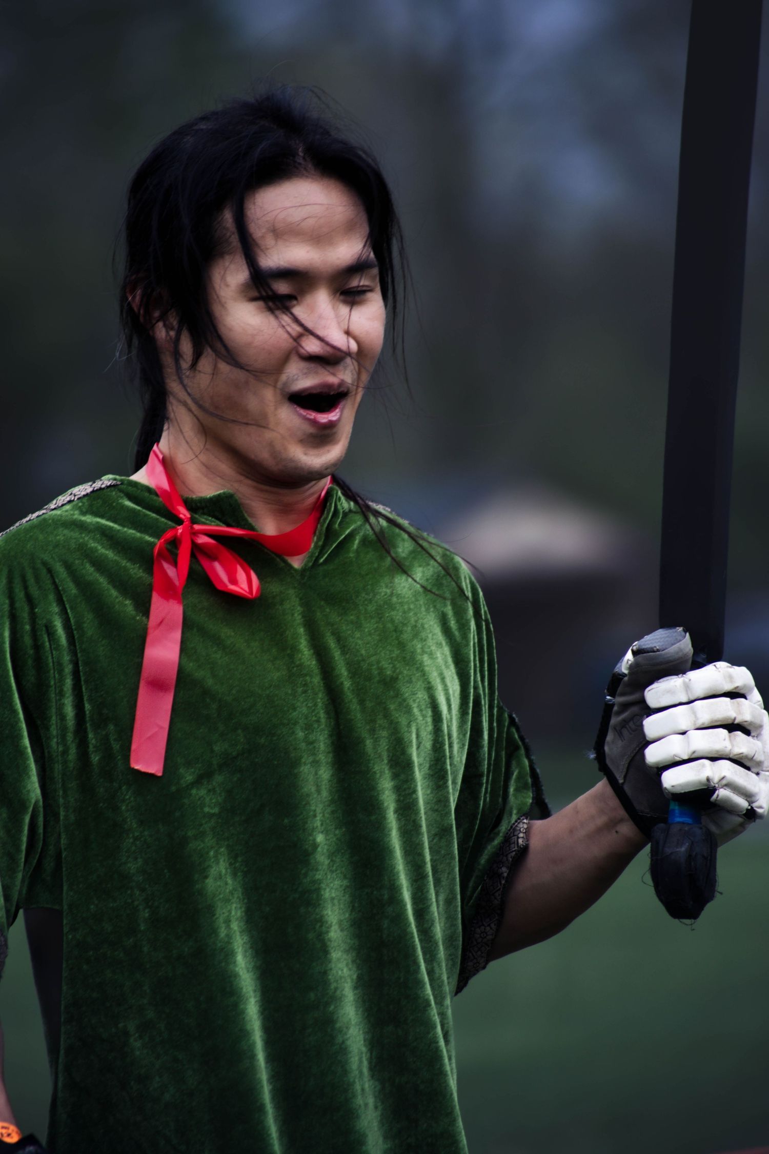 Person in green velvet costume with red accent and gloves gesturing expressively.