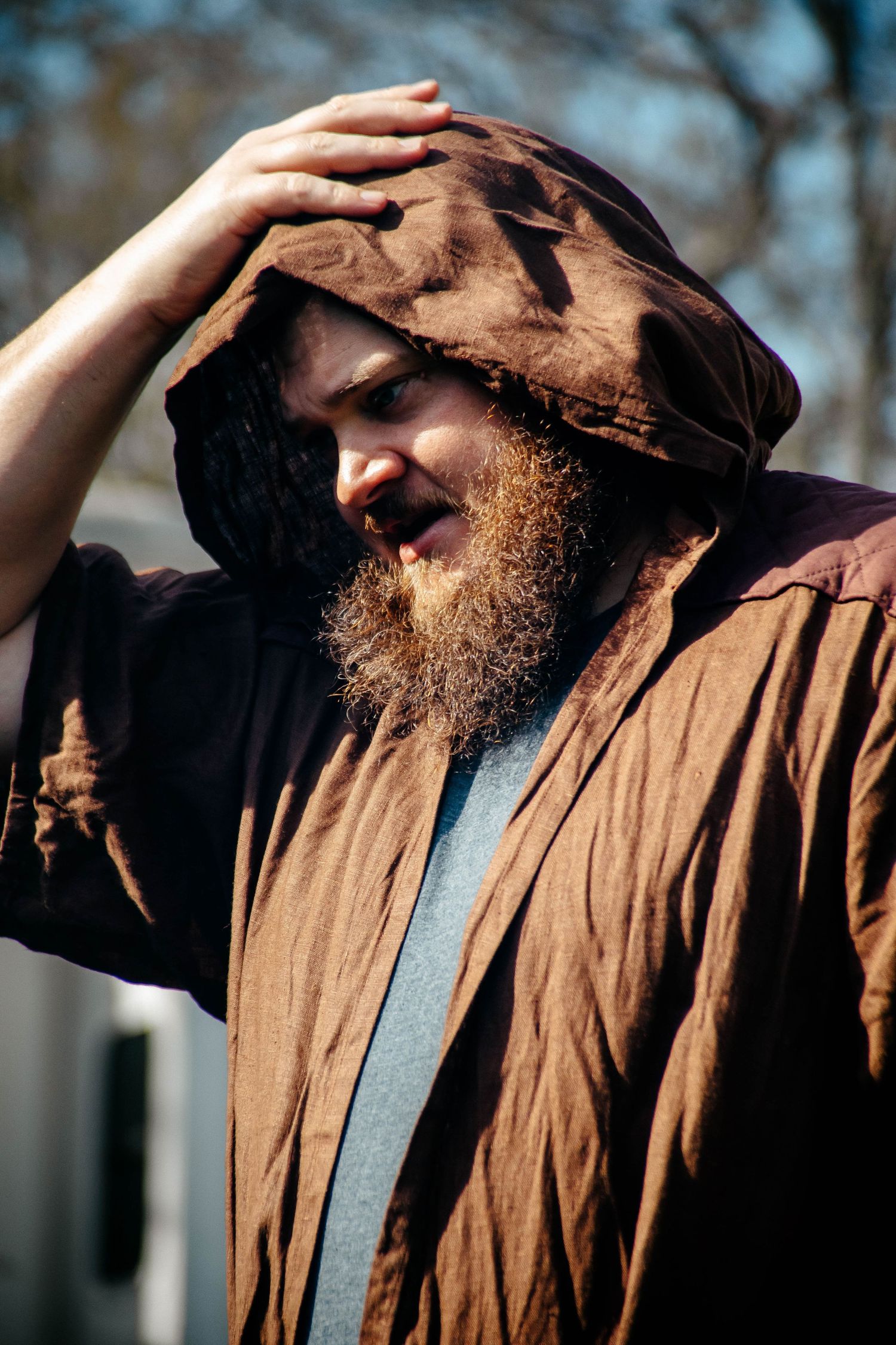 A bearded person wearing a brown jacket gazes upward in a series of four similar profile shots outdoors.