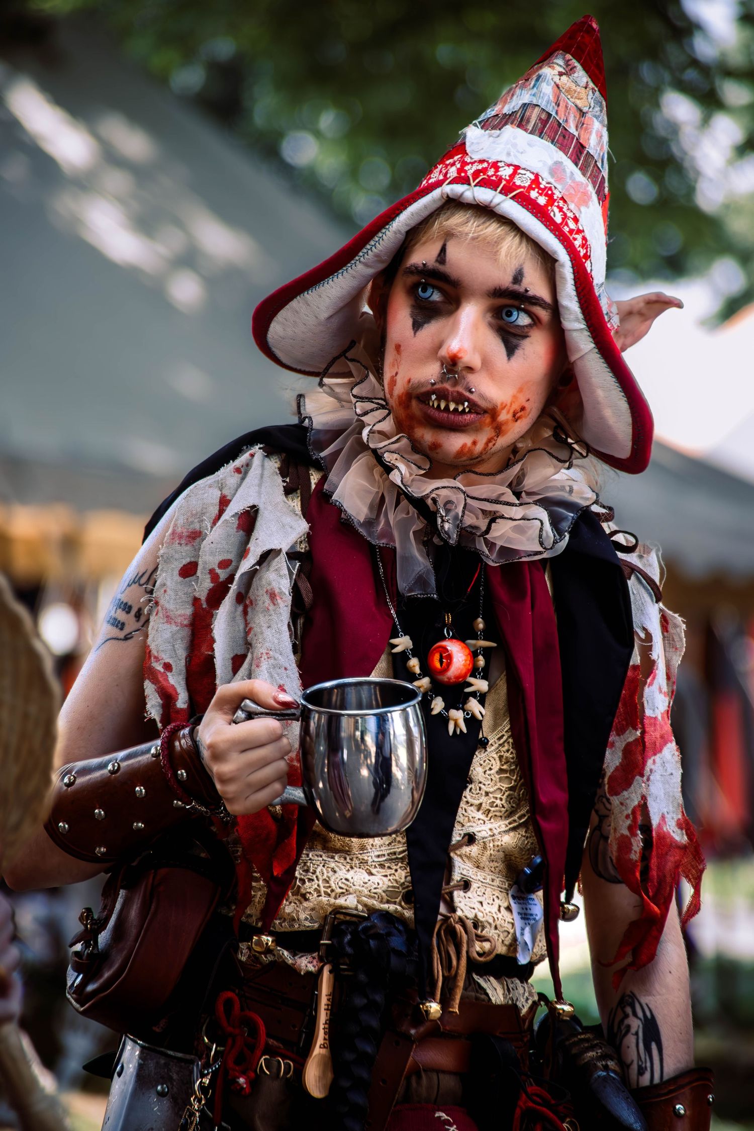 A spooky Halloween costume featuring bloody makeup, a red and white hat, and dark clothing in multiple closeup shots.