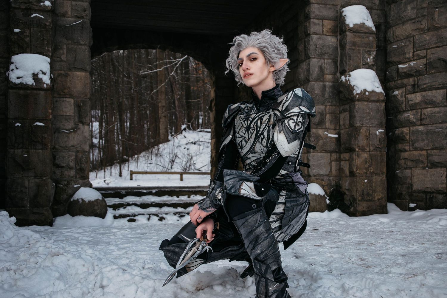 Winter fashion photoshoot against stone architecture with snow-covered ground.