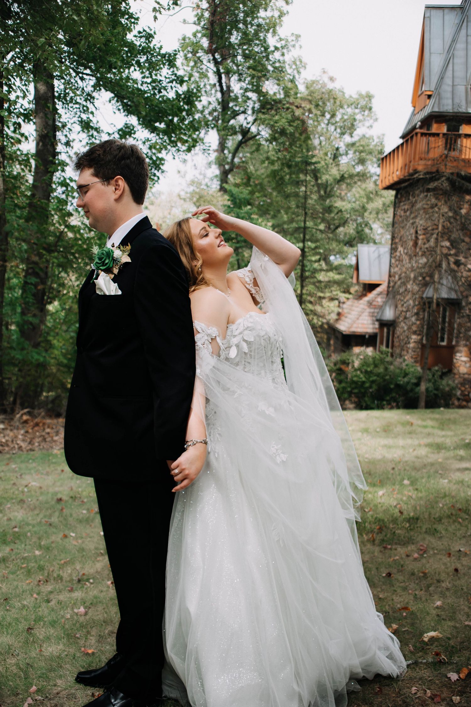 A romantic moment between newlyweds in their formal wedding attire surrounded by lush greenery outdoors.