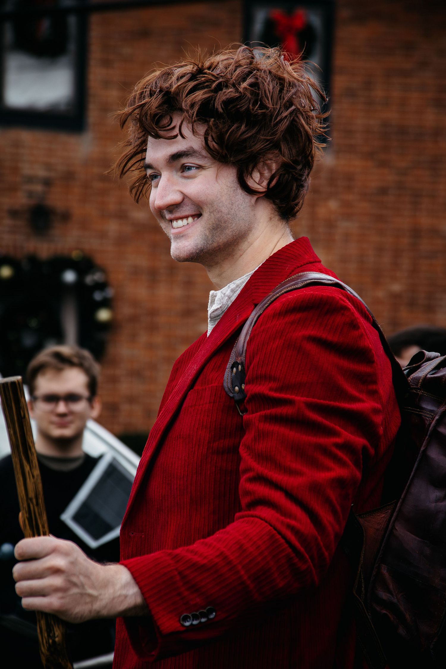 Person in a red jacket smiles while participating in a historical event.