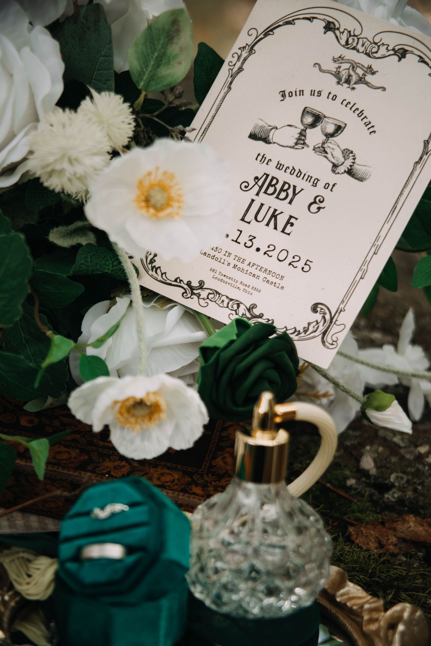 Elegant wedding invitation cards with vintage designs displayed among white flowers and decorative elements.