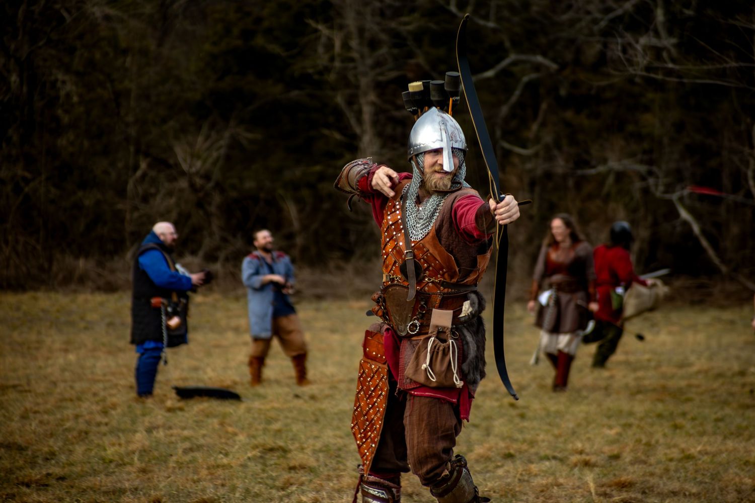 Medieval reenactors engage in sword combat during a historical battle demonstration in an open field.