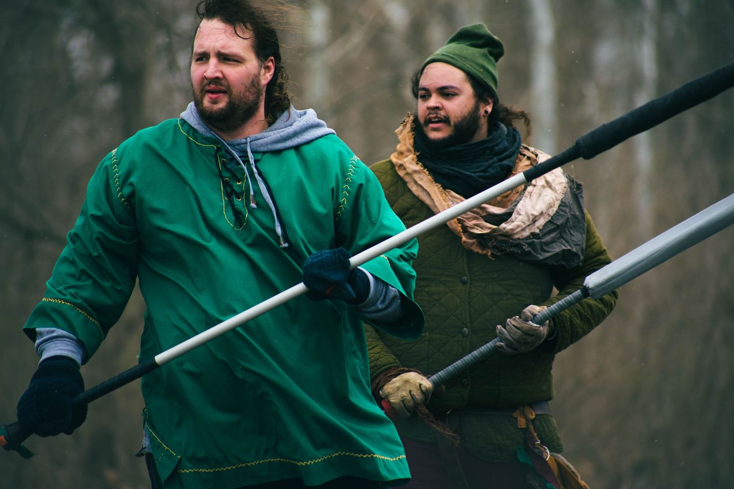 Person in green jacket aims a shotgun during outdoor sport shooting practice session.