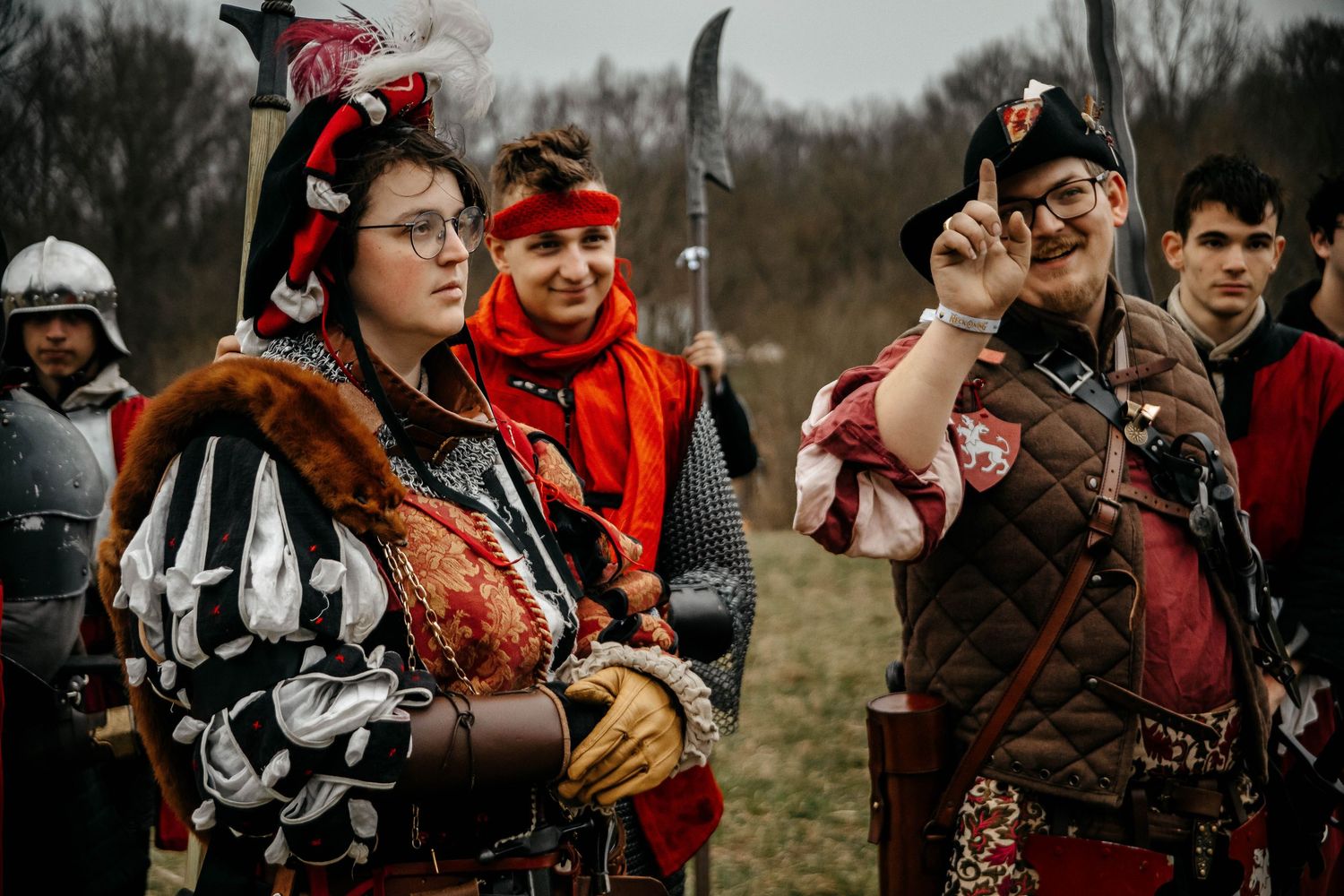 A group in medieval costumes and armor gather outdoors for a historical reenactment event.