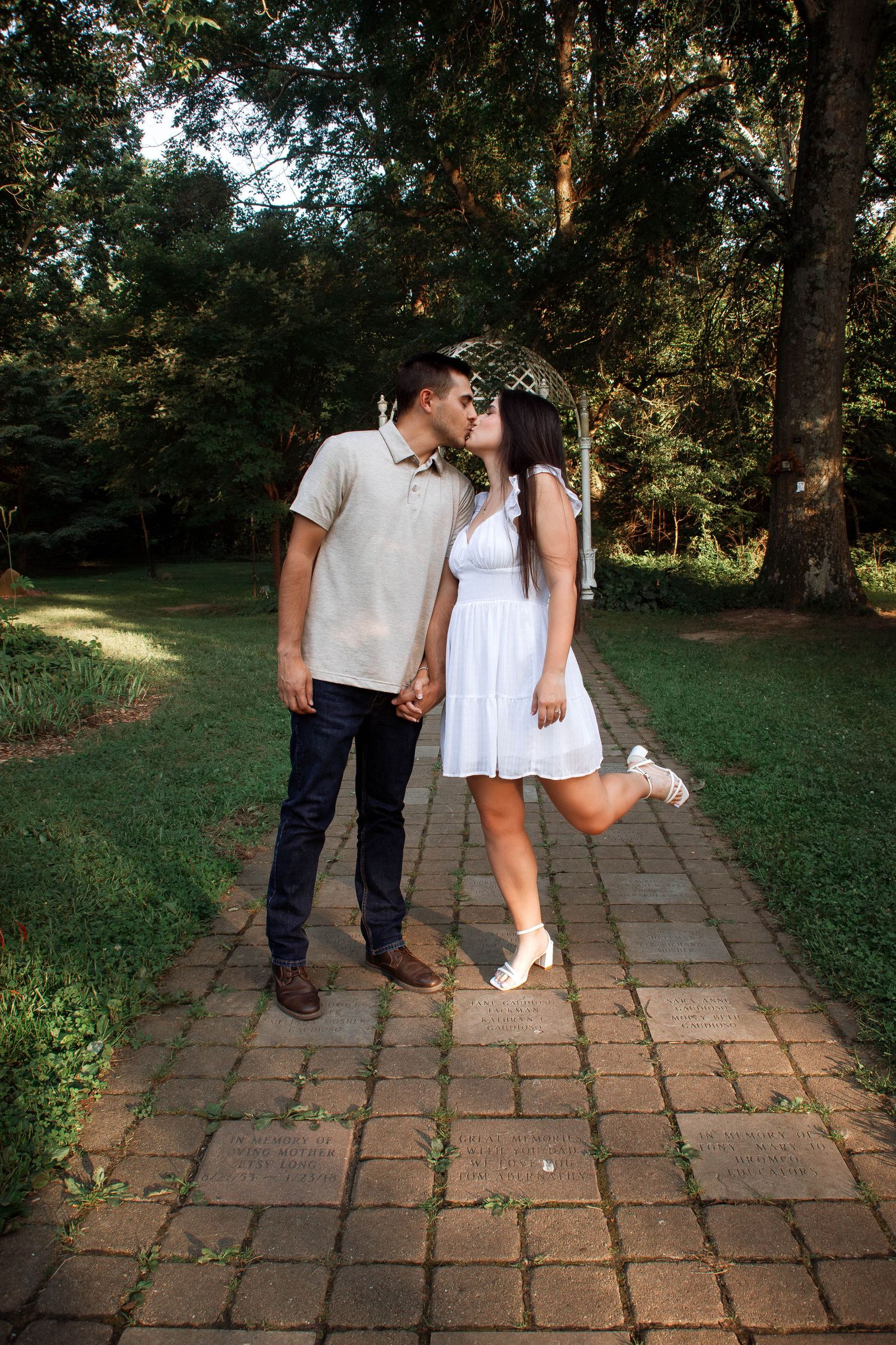 A couple walks together on a stone path through a lush garden setting.