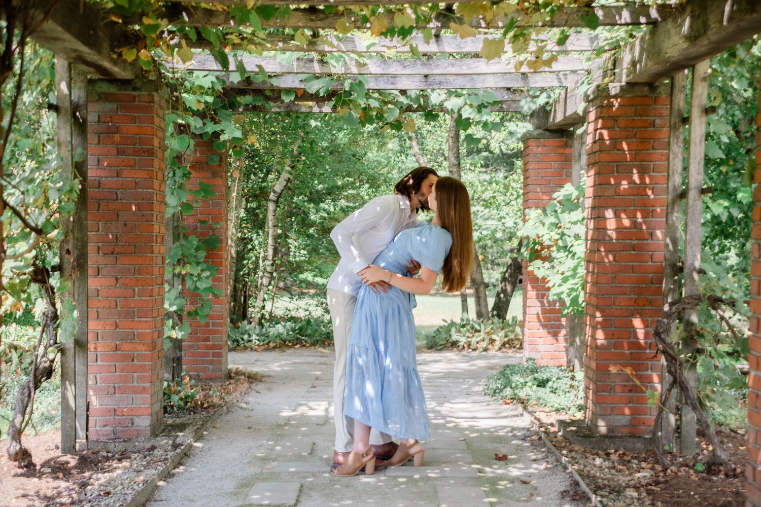 Romantic photoshoot under a vine-covered brick archway in a garden setting.
