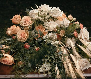 A romantic floral arrangement with peach roses, white flowers, and dried wheat stems in a vintage-inspired setting.