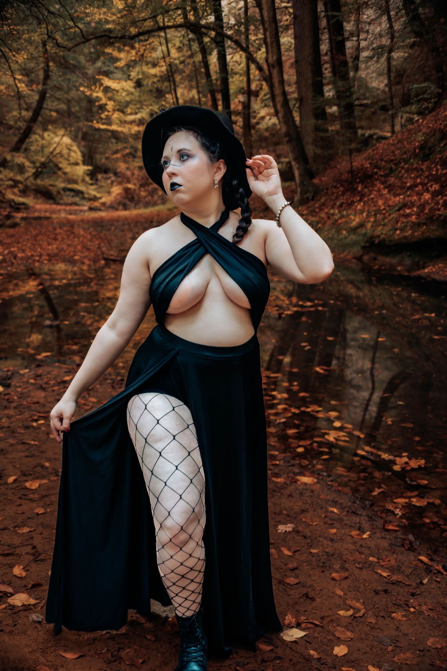 Artistic autumn forest photoshoot featuring dark gothic fashion styling against a backdrop of fallen leaves and trees.