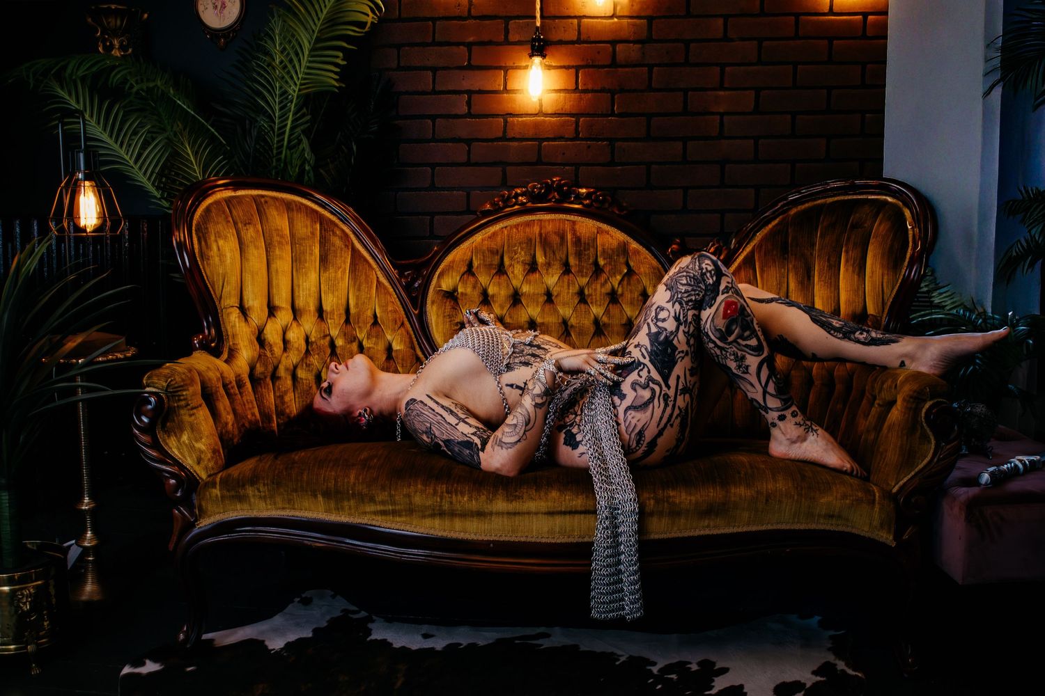 Dimly lit lounge interior with vintage gold tufted couch and hanging pendant lights creating a moody atmosphere.