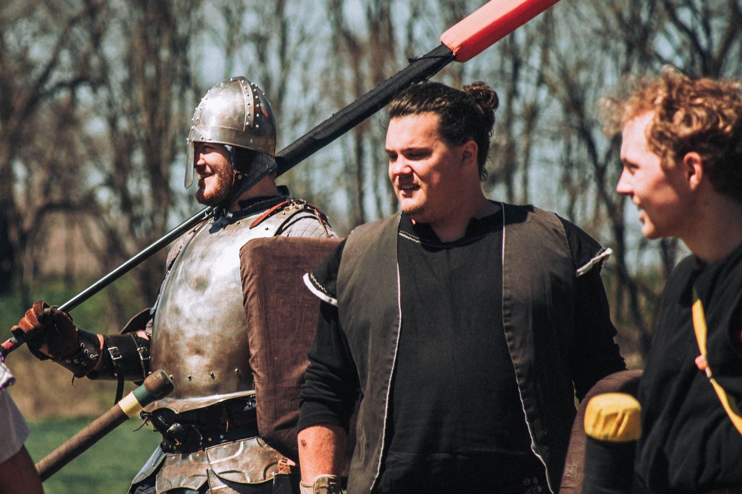 A group of people practicing archery with bows and arrows in a wooded outdoor setting during winter.