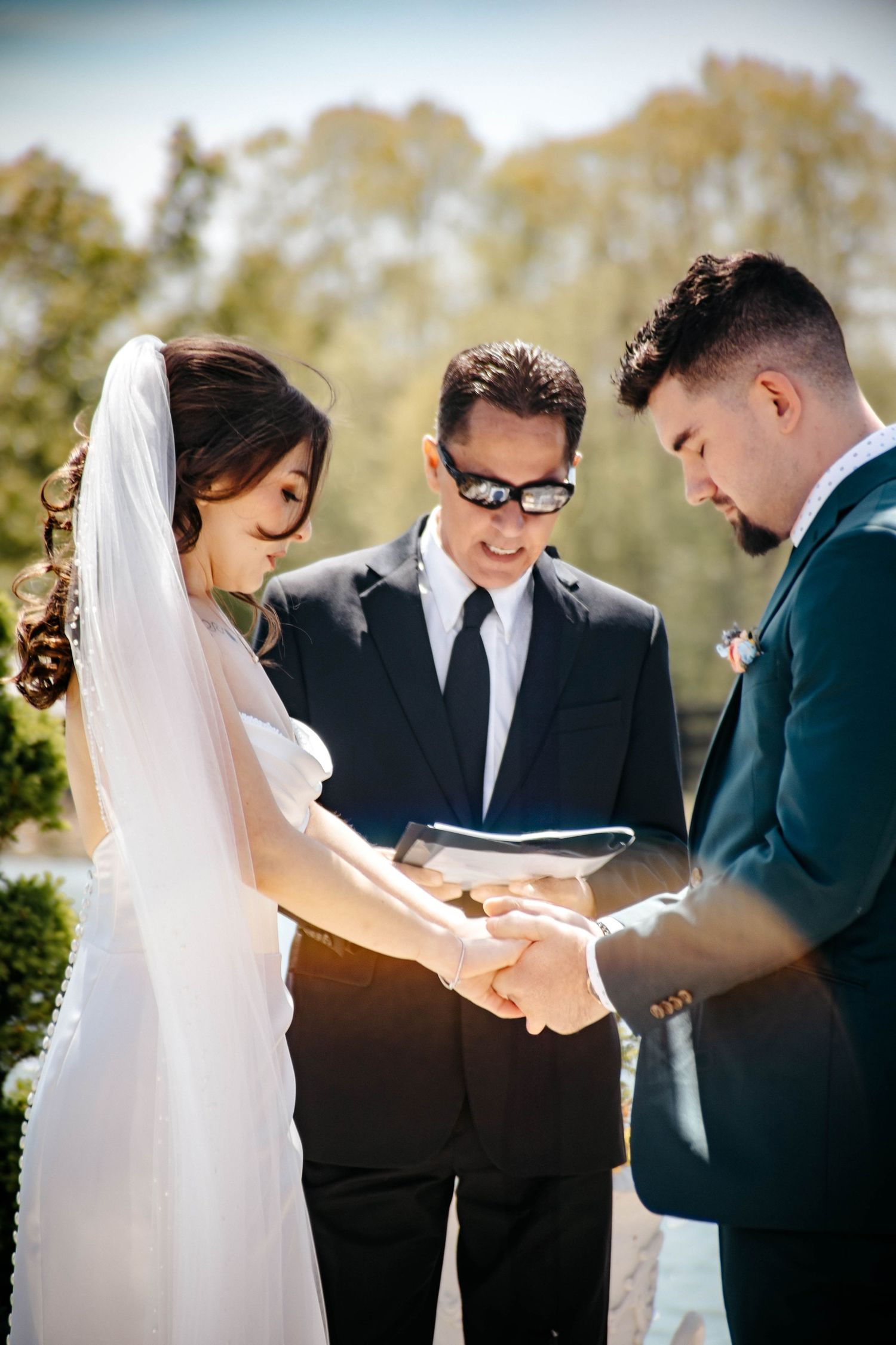 A wedding ceremony in progress with participants in formal attire outdoors.