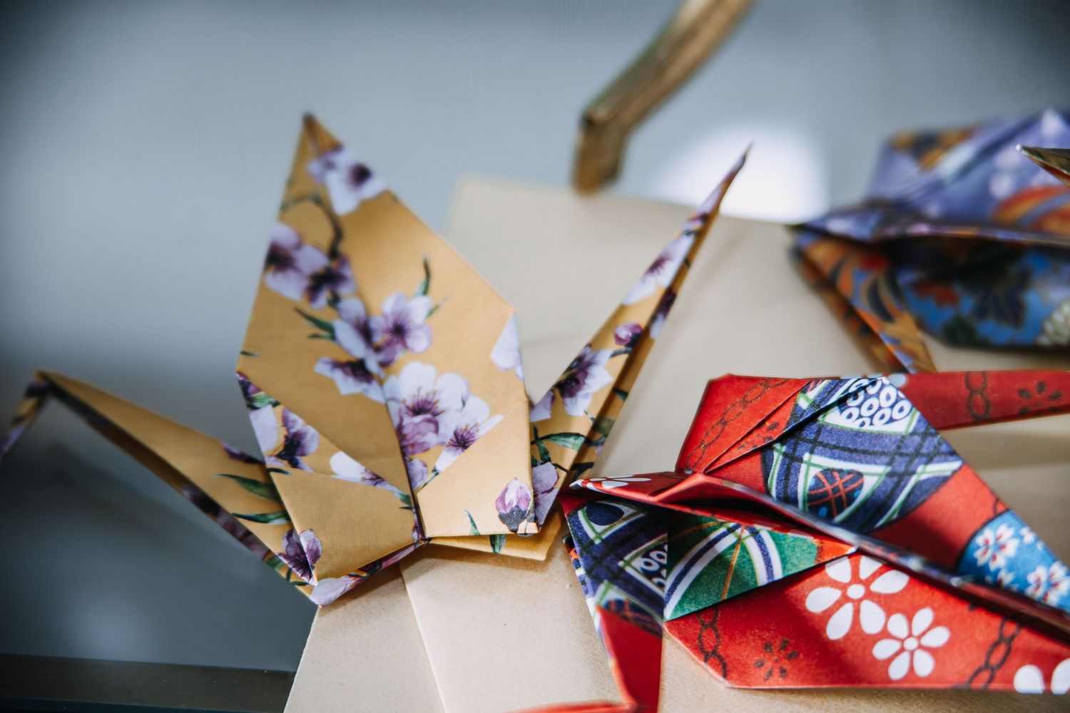 Colorful origami cranes folded from decorative Japanese paper with floral and geometric patterns displayed on a white surface.