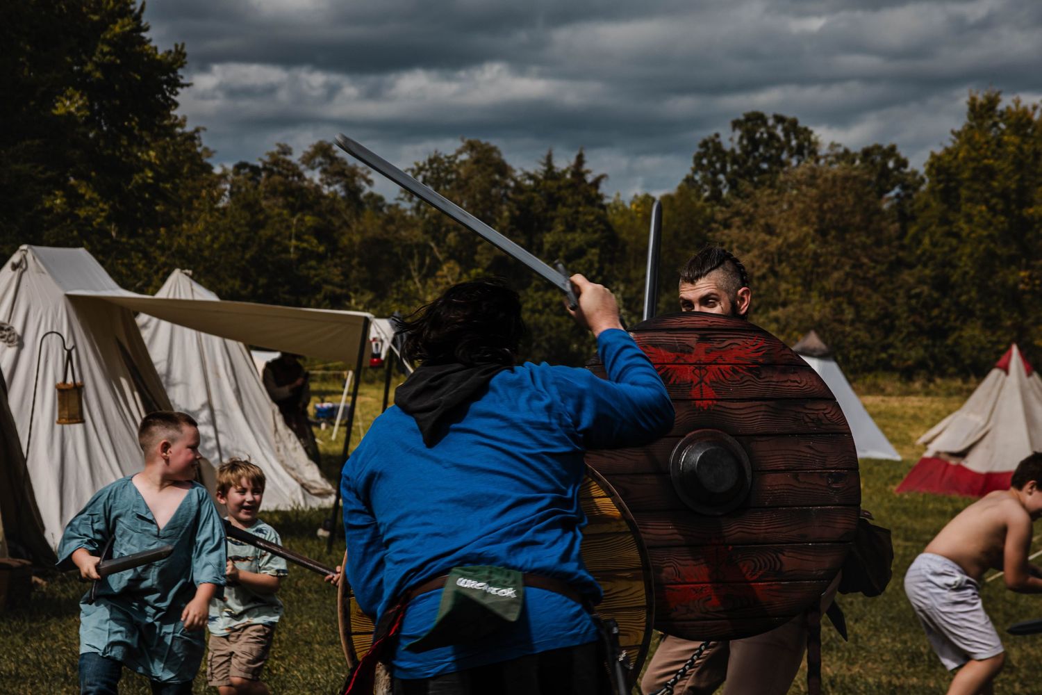 Historical reenactors demonstrate sword fighting techniques at an outdoor medieval festival.