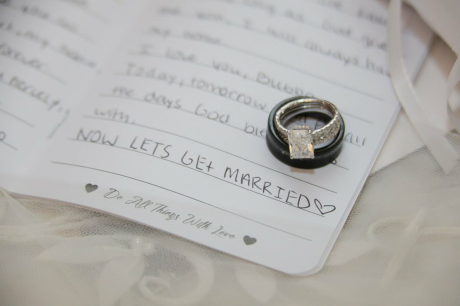 Wedding rings resting on a handwritten note saying Now Lets Get Married, symbolizing a romantic wedding day moment.
