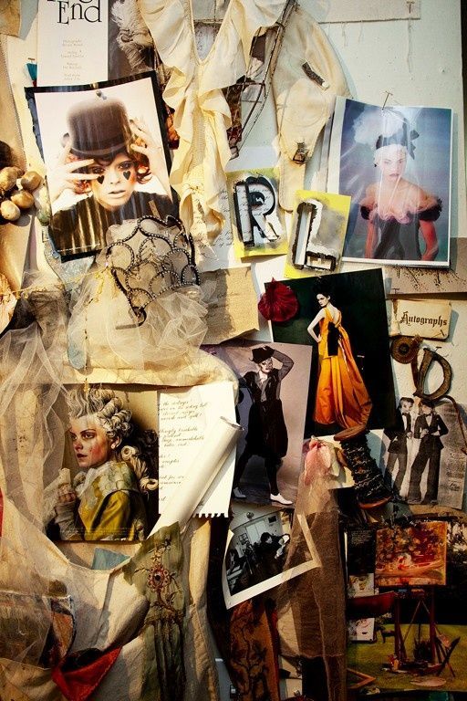 A vintage mood board with fashion photographs and sketches pinned on a wall with draped fabric and lace elements.