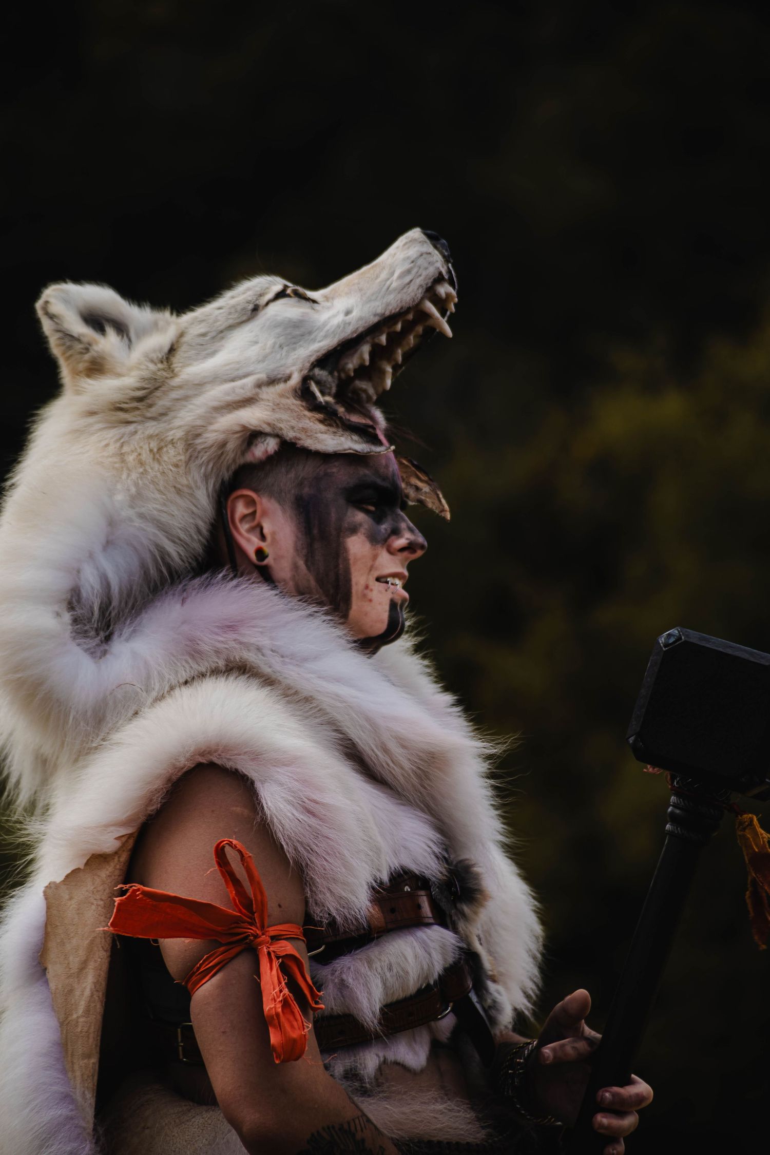 A person wearing a white fur headdress and orange top poses against a dark background in a series of artistic shots.