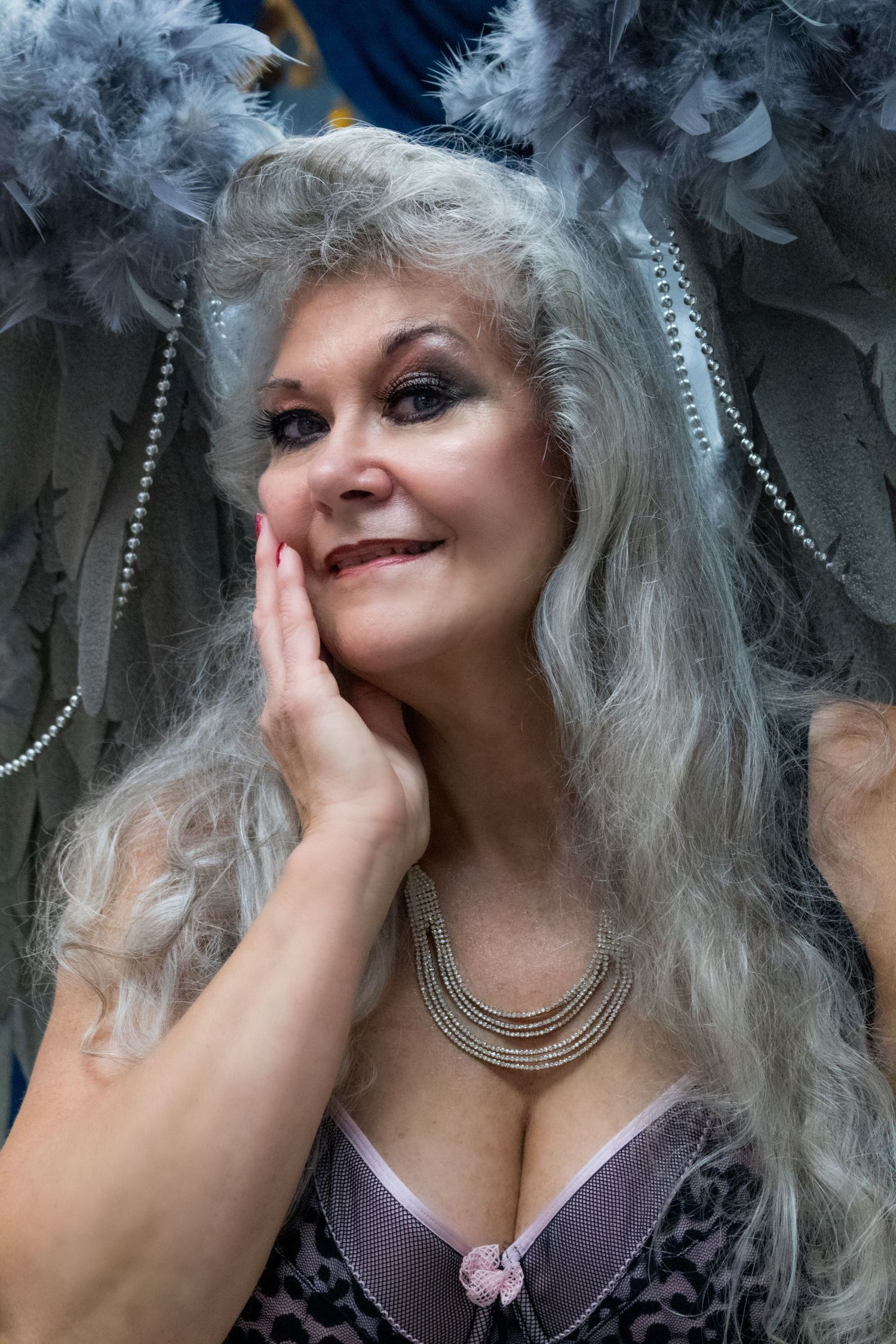 Glamour portrait with silver hair, feather accessories and vintage-style jewelry.