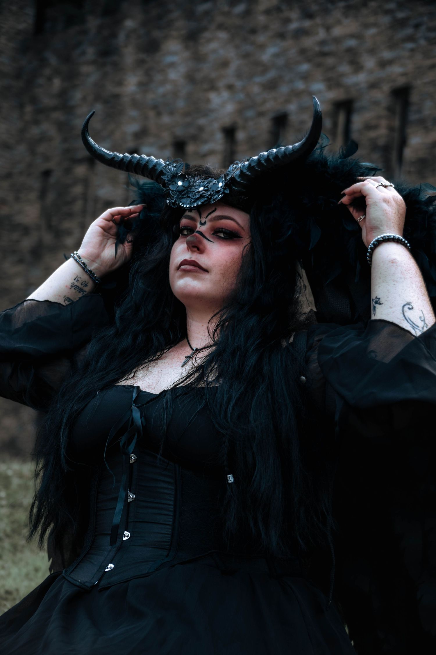 Dark gothic photo series showing dramatic poses against stone wall in black clothing.