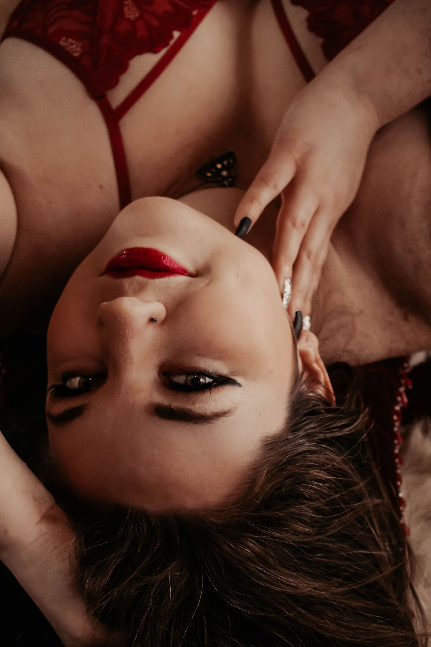 Close-up boudoir photo showing red lipstick and dark eye makeup in moody lighting.