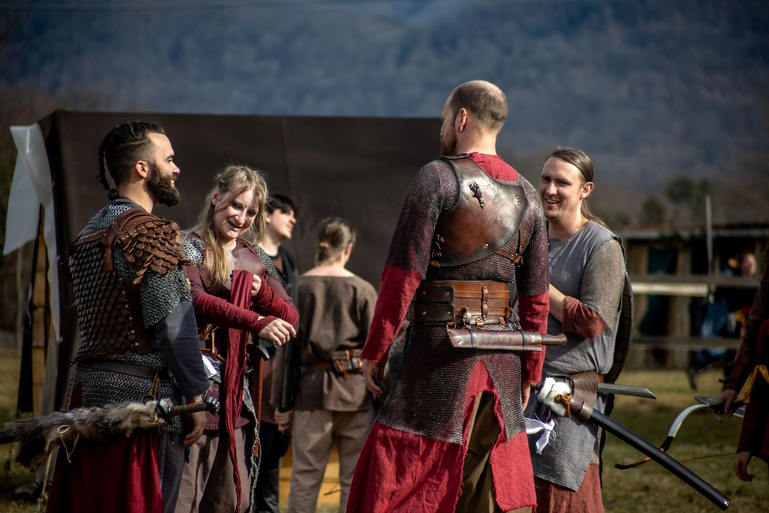 A group of people dressed in medieval costumes gather outdoors for a historical reenactment event.